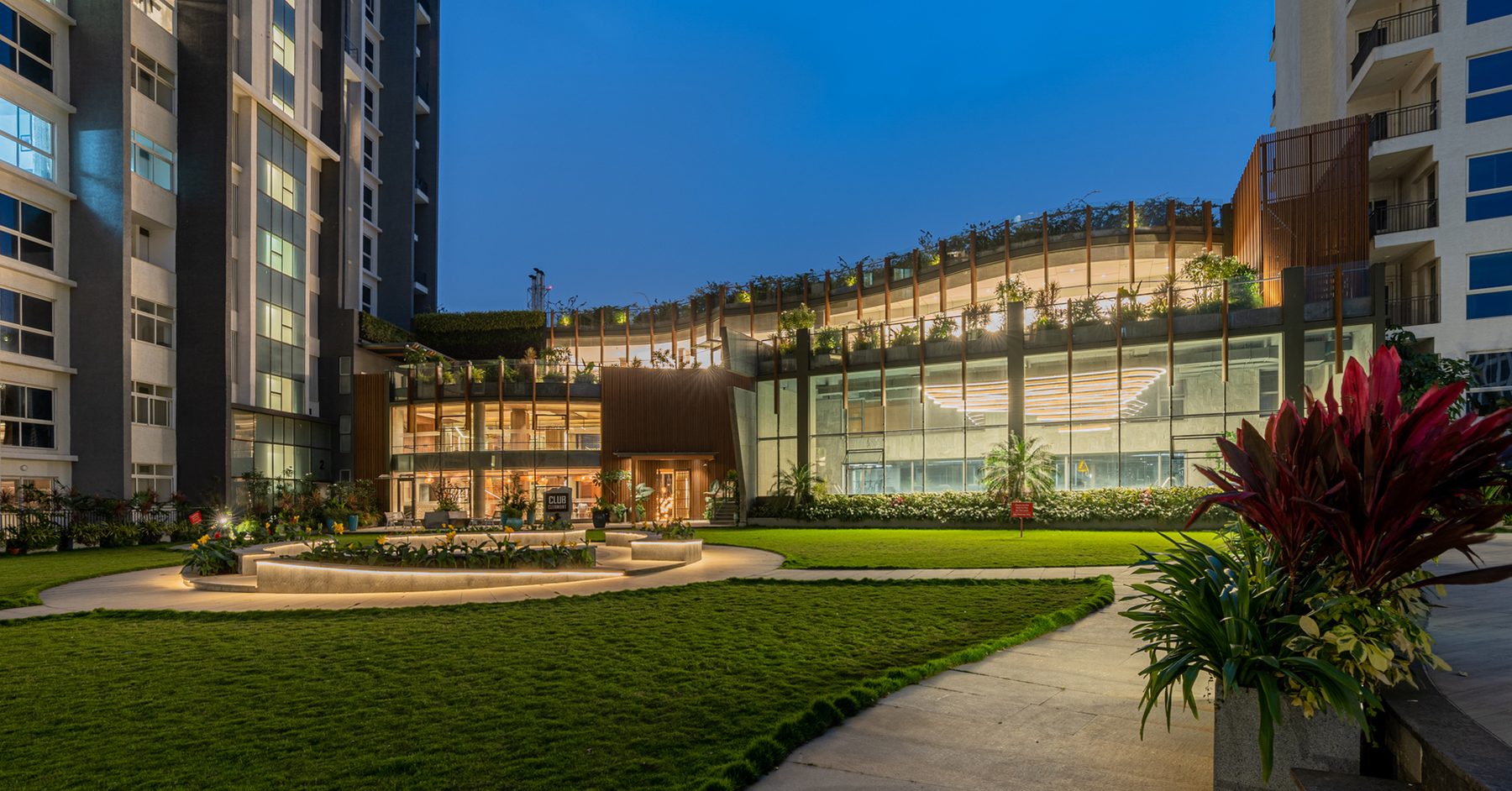 A landscaped courtyard and lit building at dusk, photographed by Capturekraft